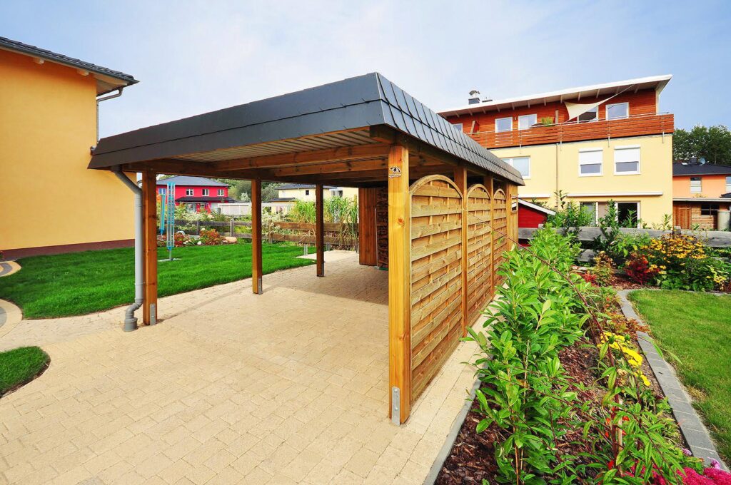 Flachdach-Einzelcarport aus Holz mit schwarzer Schindelblende und Abstellraum
