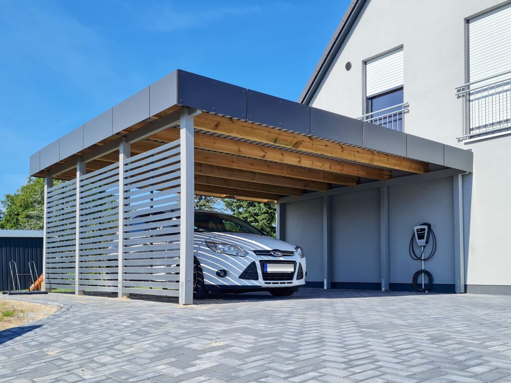 Flachdach-Doppelcarport aus Holz mit anthrazitfarbener HPL-Blende am Haus