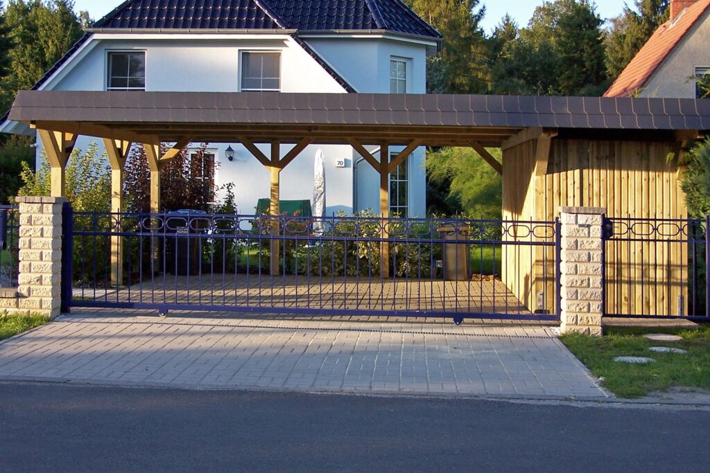 Maßgefertigter Holzcarport mit integriertem Abstellraum und dunkler Blende vor einem Wohnhaus