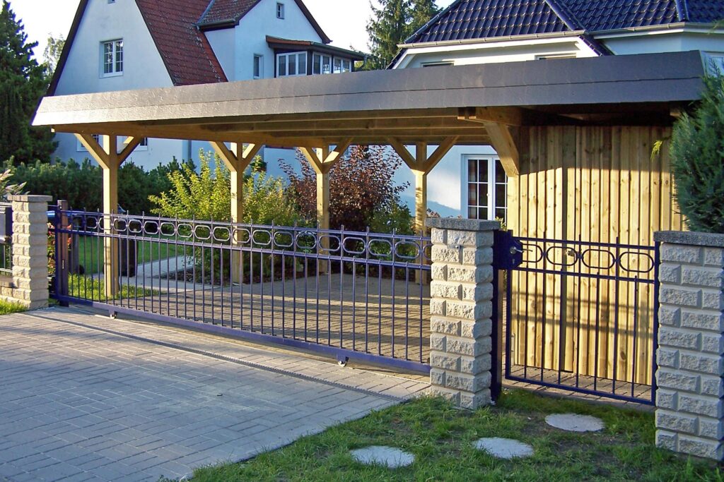 Maßgefertigter Holzcarport mit integriertem Abstellraum und dunkler Blende vor einem Wohnhaus