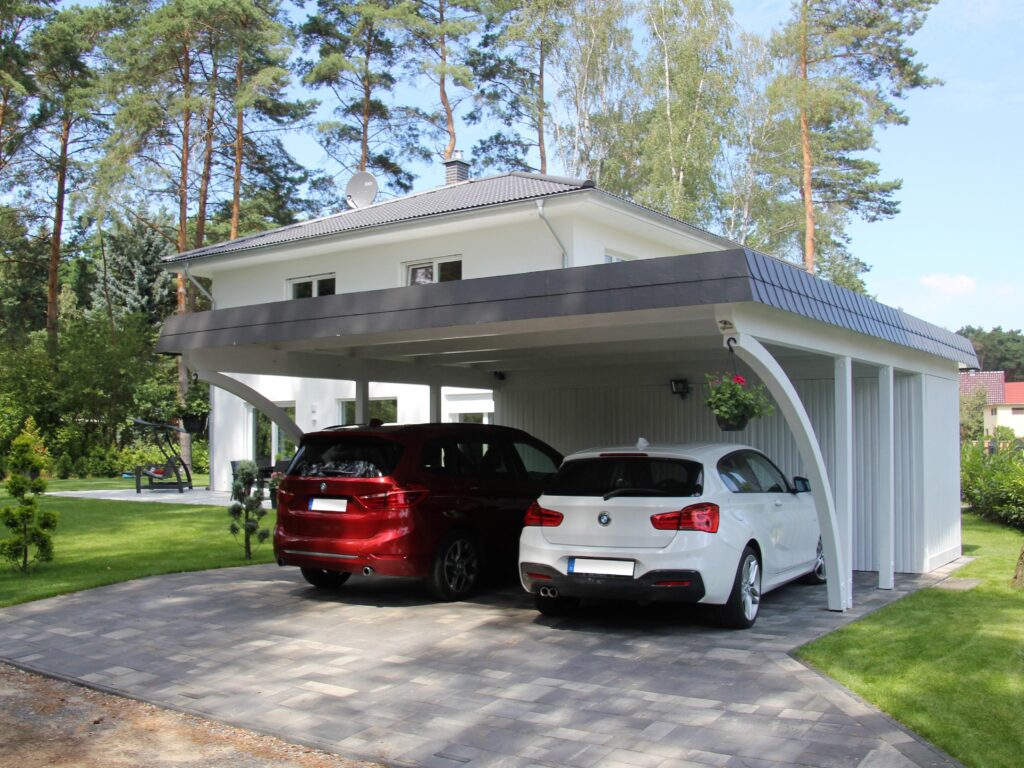 Moderner weißer Doppelcarport mit Rundbögen, der zwei Autos Wetterschutz bietet