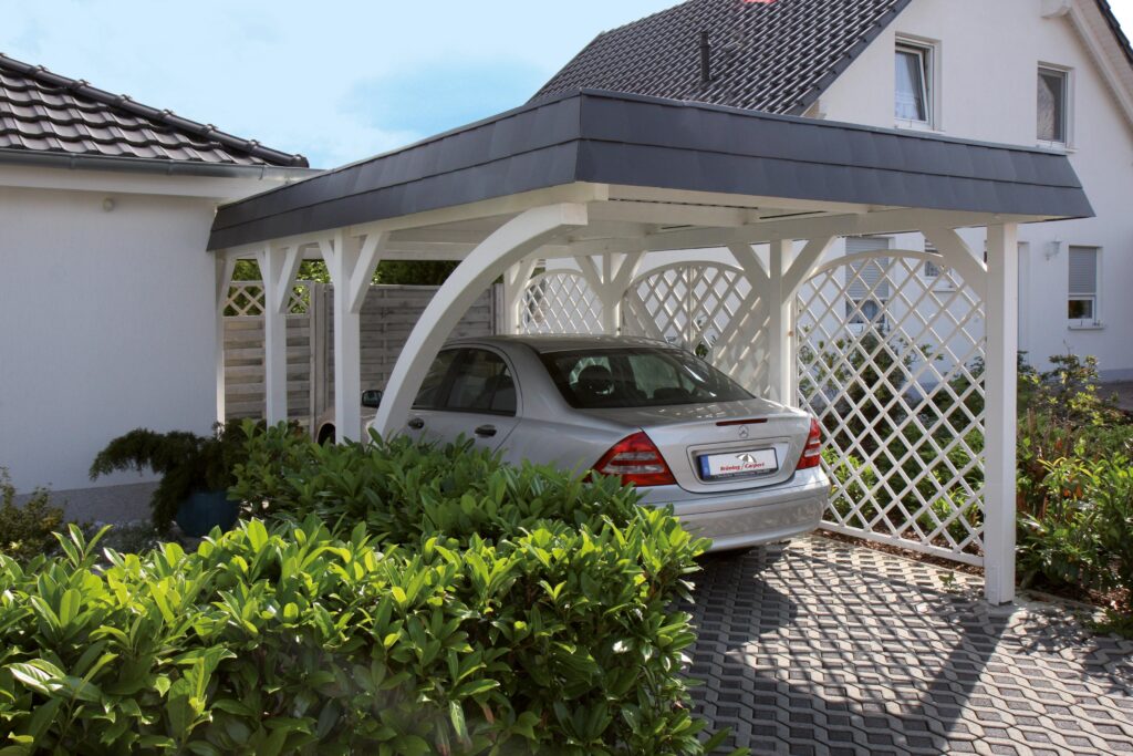 Weißer Rundbogen-Carport aus Leimholz, der sich elegant in die Hausarchitektur einfügt