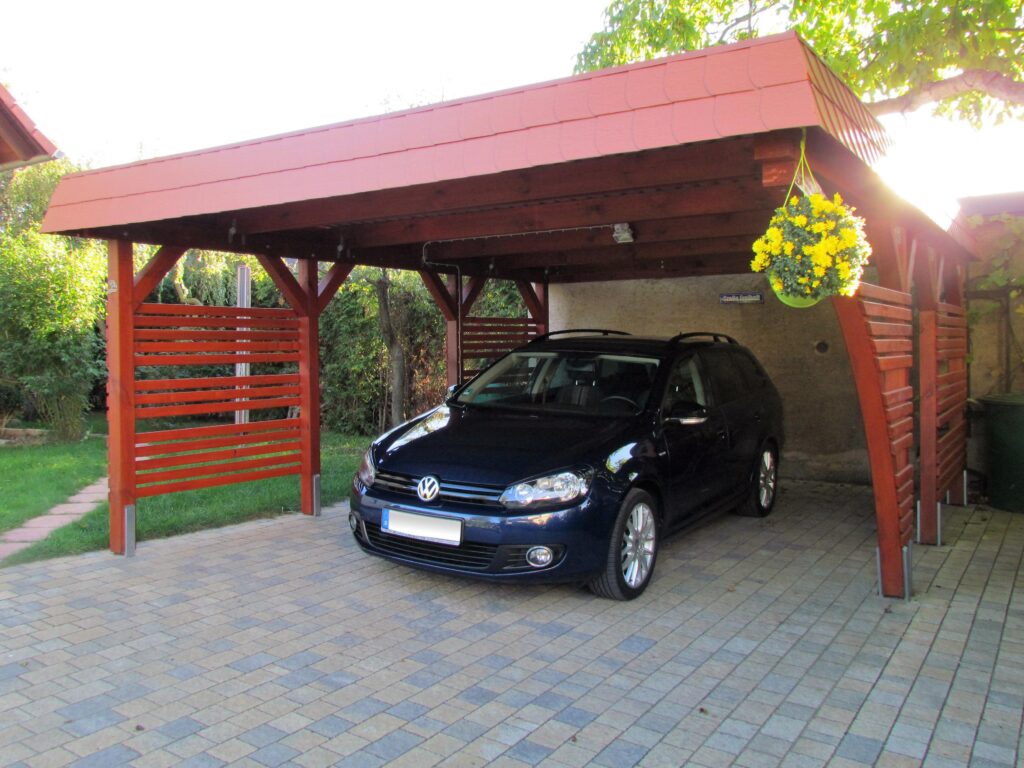 Carport mit markanten Rundbogen-Elementen aus Holz und seitlichem Sichtschutz schützt das parkende Auto