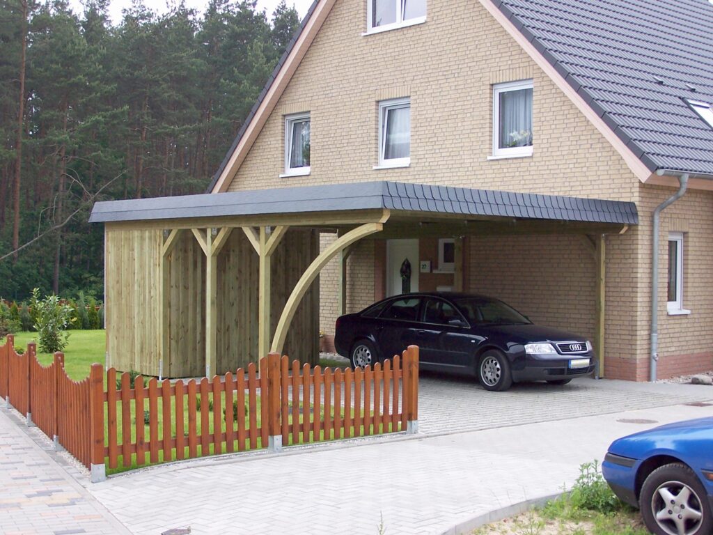 Rundbogen-Carport aus Holz mit geschwungenem Bogen und integriertem Abstellraum, angelehnt an ein Haus