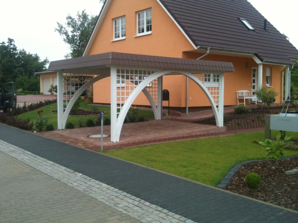 Eleganter Bogengang Carport mit weißen Bogenpfosten und Rankgittern vor einem Wohnhaus