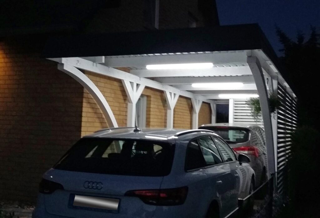Weißer Rundbogen-Holzcarport für zwei Autos, beleuchtet bei Nacht