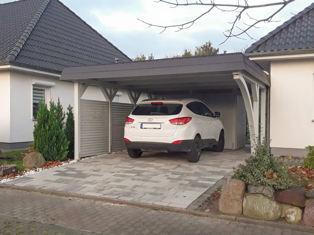 Rundbogen-Carport mit Abstellkammer und parkendem Auto.