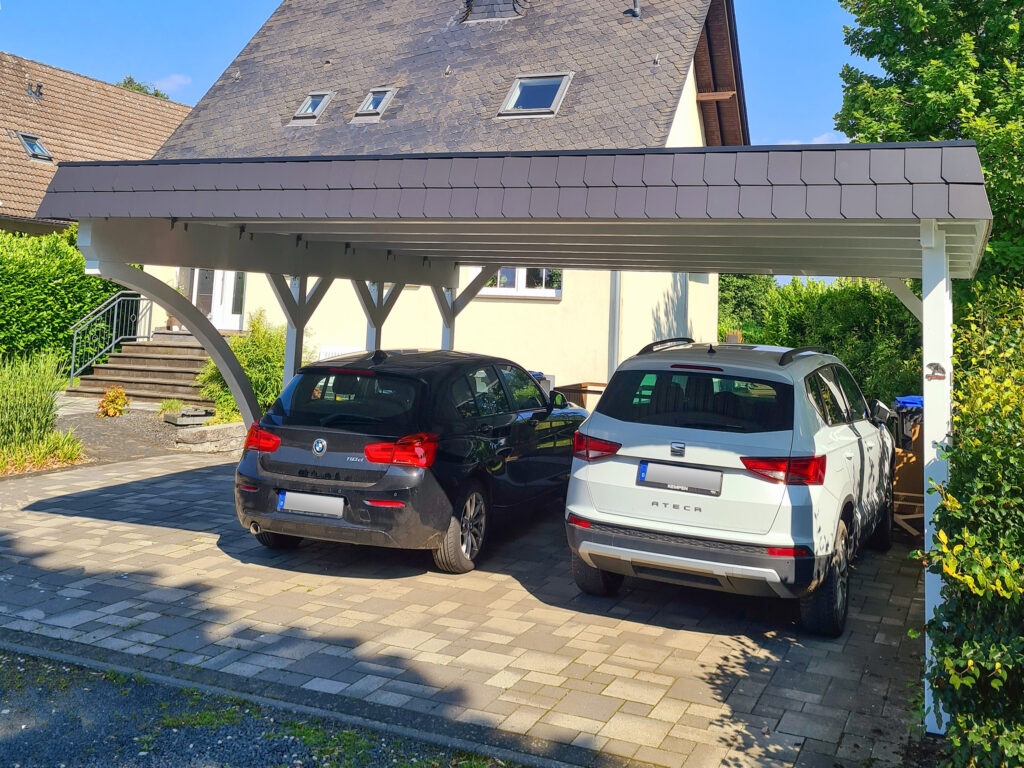 Rundbogen-Carport mit Schindelblende für zwei Autos vor einem Wohnhaus