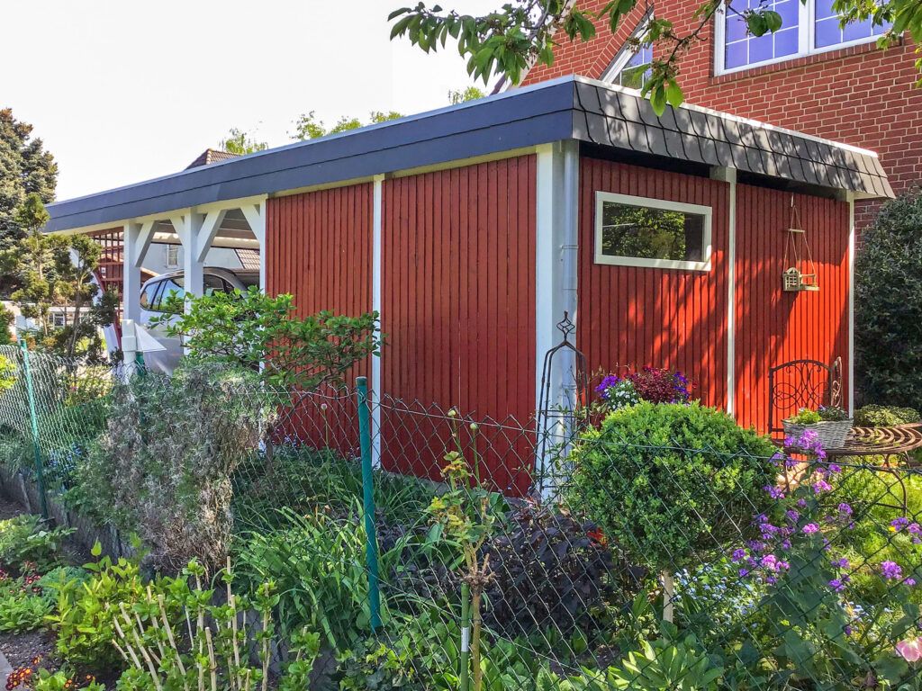 Moderner Rundbogen Carport aus Holz mit roter Abstellkammer und weiß lackierten Pfosten