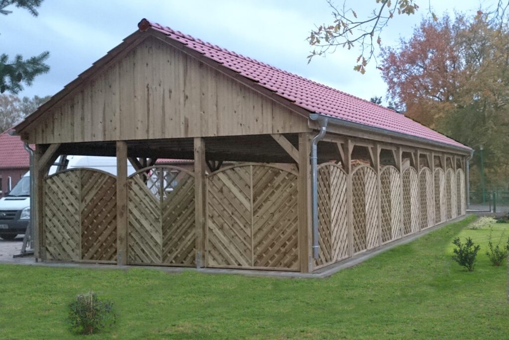 Carport-Reihenanlage mit Spitzdach und roten Dachsteinen und seitlichem Sichtschutz